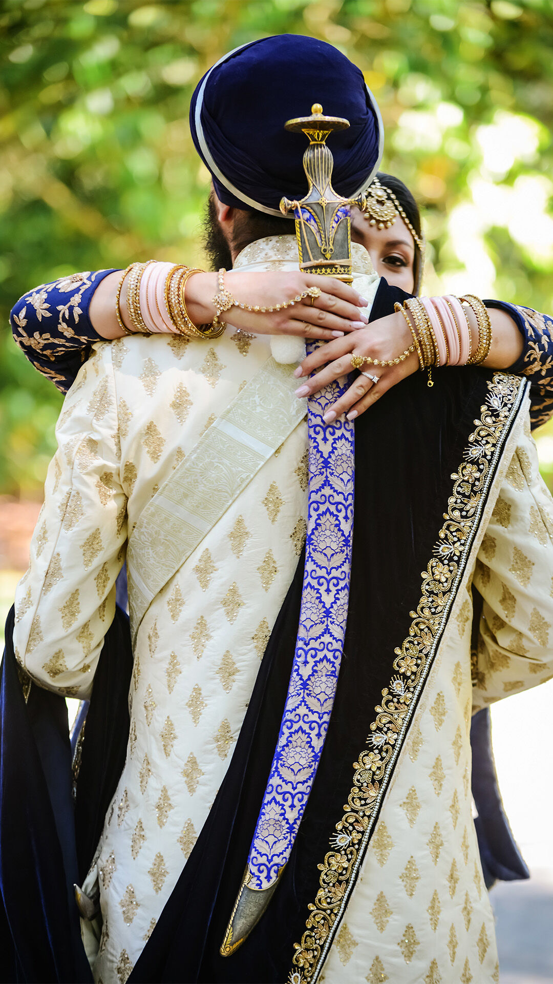 A Punjabi bride hugging her groom with a traditional punjabi sword in hand 